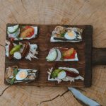 Top view of holiday appetizers on a wooden board with festive elements, creating a cozy rustic feel.