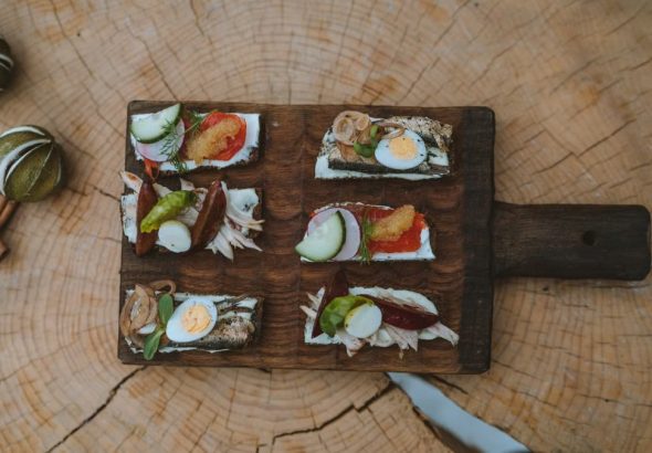 Top view of holiday appetizers on a wooden board with festive elements, creating a cozy rustic feel.